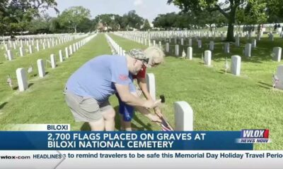 Volunteers place flags on gravesites at Biloxi National Cemetery